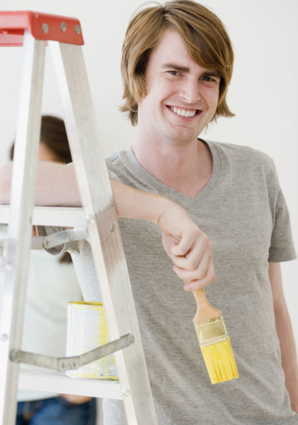 Man holding paintbrush next to ladder. Date : 2007