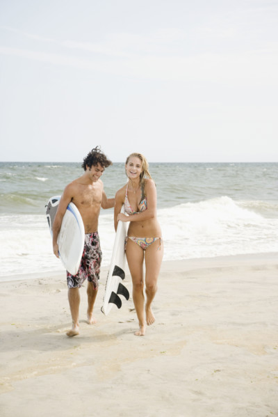 Couple carrying surfboards at beach. Date : 2007