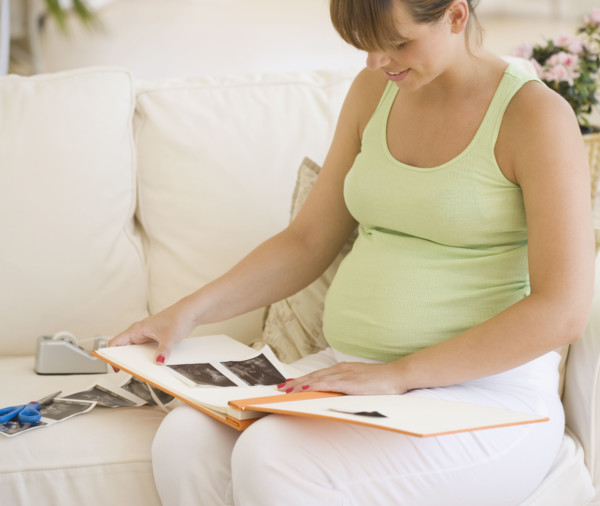 Pregnant woman putting ultrasound in photo album. Date : 2007