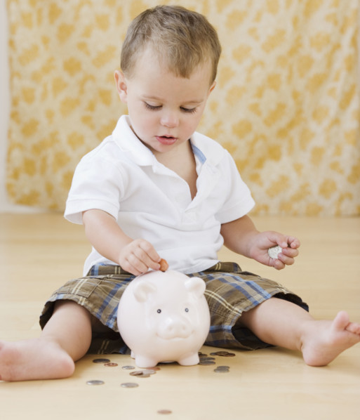 Baby putting coins in piggy bank. Date : 2007