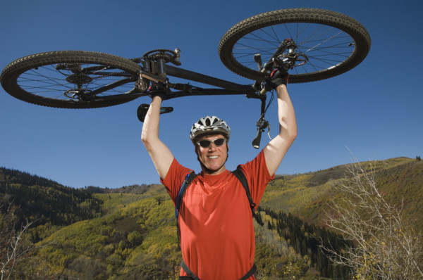 Man holding mountain bike over head, Utah, United States. Date : 2007