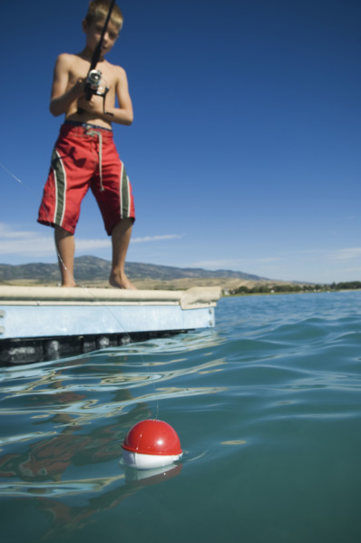 Boy fishing off dock in lake, Utah, United States. Date : 2007