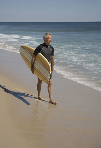 Man carrying surfboard at beach.