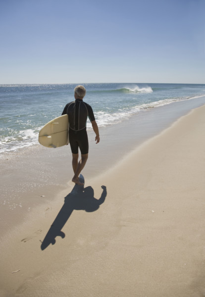 Man carrying surfboard at beach.