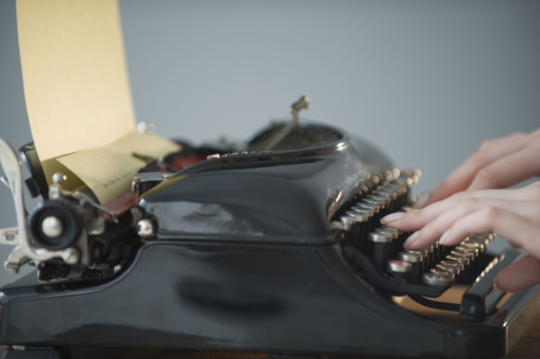Woman typing on antique typewriter.
