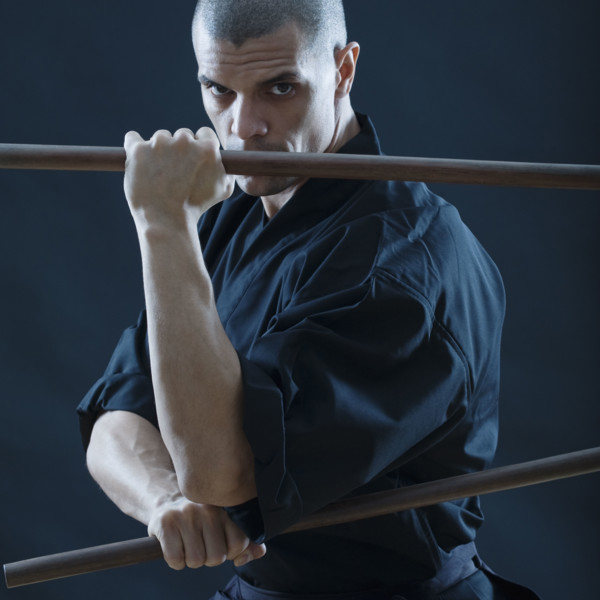 Hispanic male holding sticks in fighting stance.