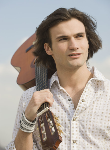 Man holding guitar on shoulder.