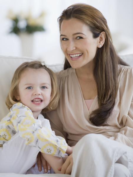 Mother and daughter sitting on sofa.