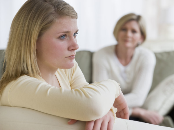 Teenaged girl looking away from mother.