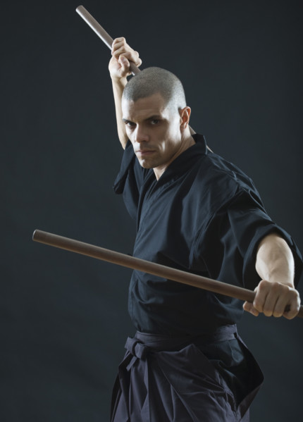 Hispanic male holding sticks in fighting stance.