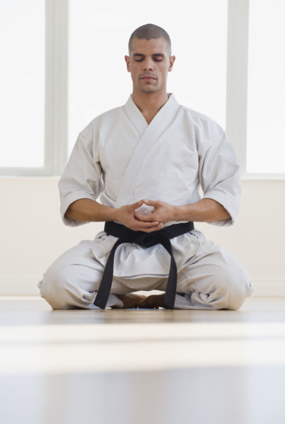 Hispanic male karate black belt meditating.