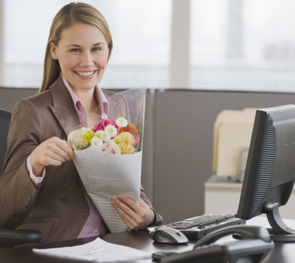 Businesswoman holding bouquet of flowers.