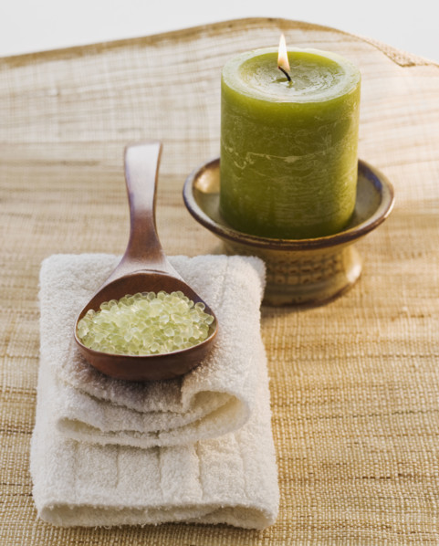 Bath salt in spoon next to candle.