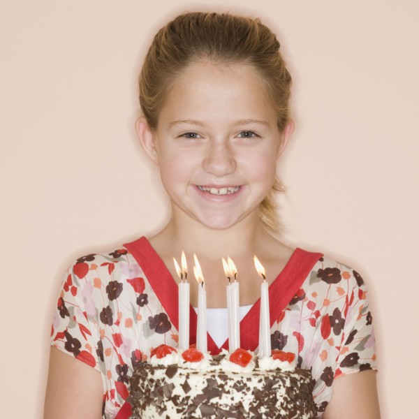 Girl holding birthday cake with lit candles.