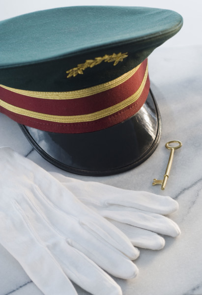 Doorman’s hat, gloves and key on table.