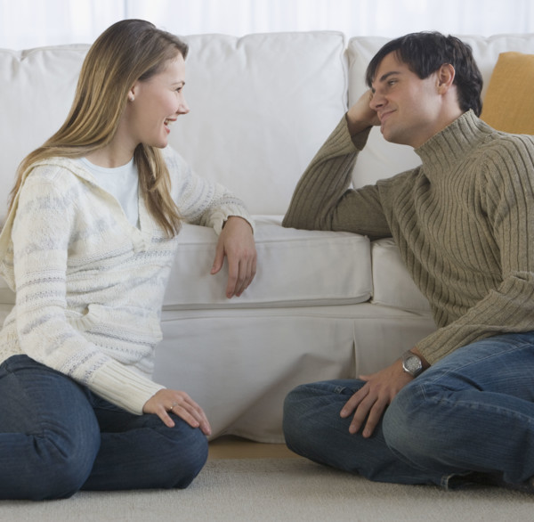 Couple sitting on floor talking.