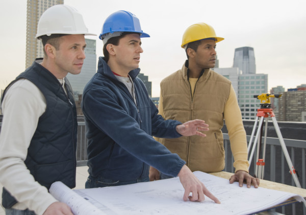 Multi-ethnic construction workers with blueprints.