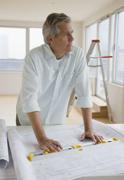 Man with level and blueprints.