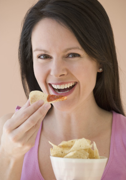 Woman eating chips and dip.
