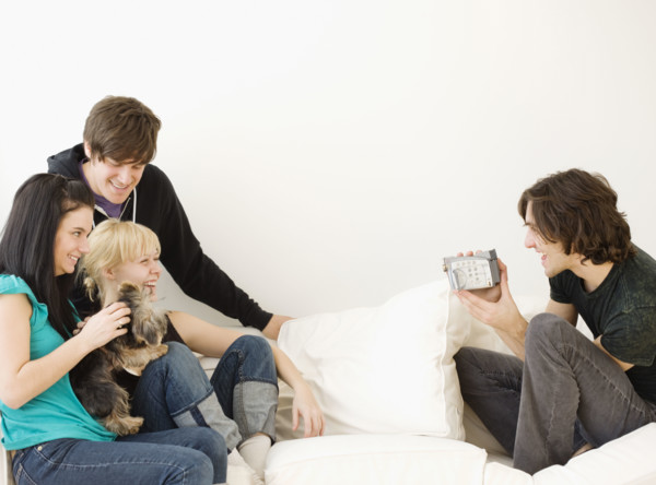Man video recording friends on sofa. Date : 2008