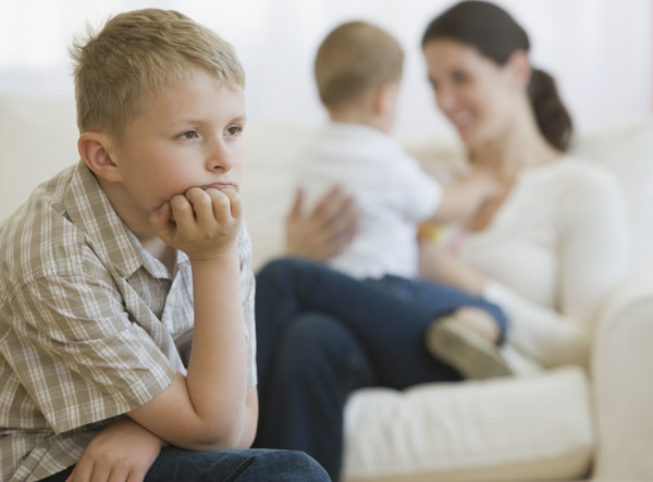 Boy thinking in front of mother and baby.