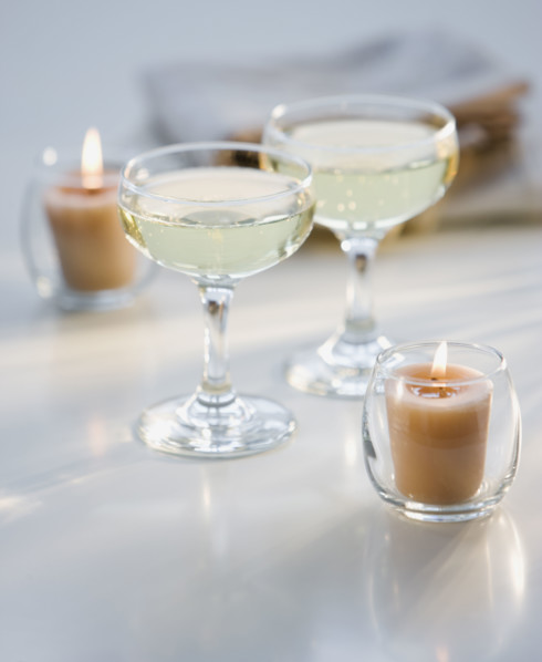 Glasses of champagne next to candles.