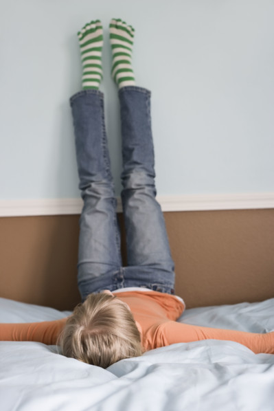 Girl laying on bed with feet on wall. Date : 2008