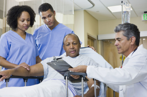 African man in hospital gurney looking at clipboard. Date : 2008