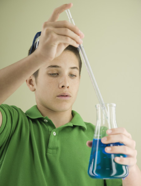 Boy measuring liquid in beaker. Date : 2008