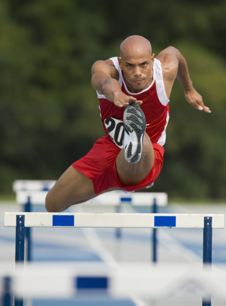 Runner jumping over hurdle.