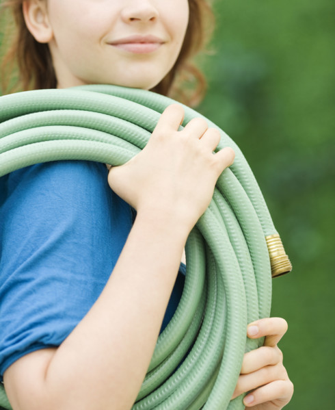 Teenage girl carrying garden hose. Date : 2008