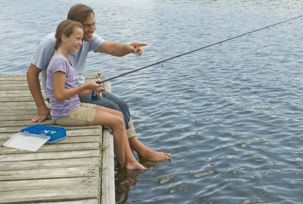 Father and daughter fishing off dock.