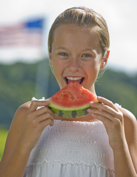 Girl eating watermelon outdoors.