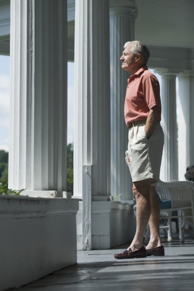 Senior man standing on porch.