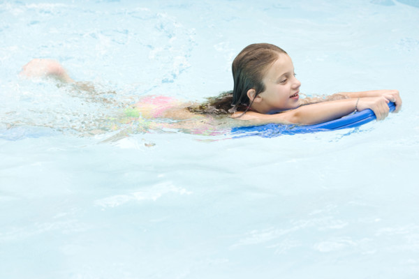 Girl using kickboard in swimming pool. Date : 2008
