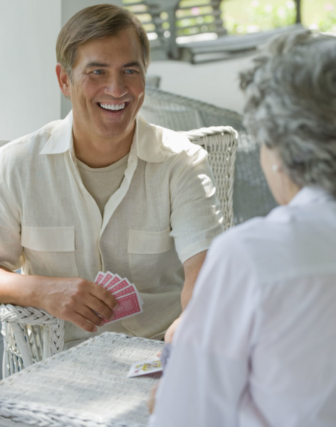 Mother and adult son playing card game on porch.