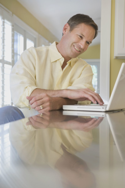 Man looking at laptop in kitchen. Date : 2008