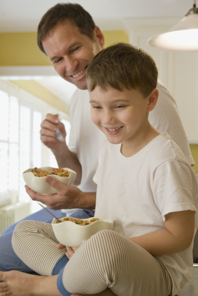 Father and son eating breakfast on kitchen counter. Date : 2008