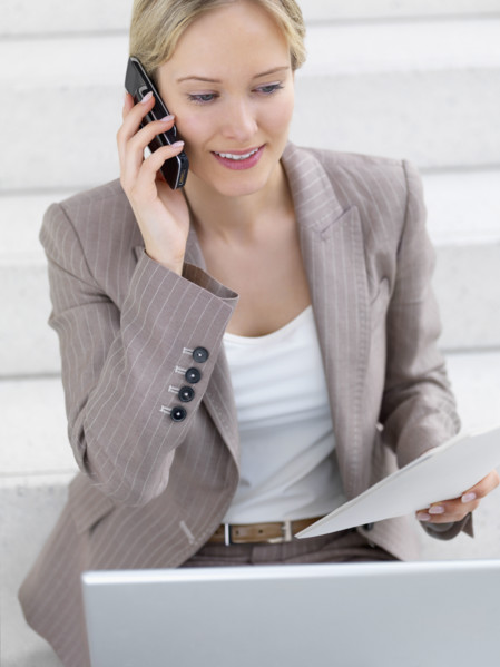 Businesswoman working on laptop and talking on cell phone. Date : 2008