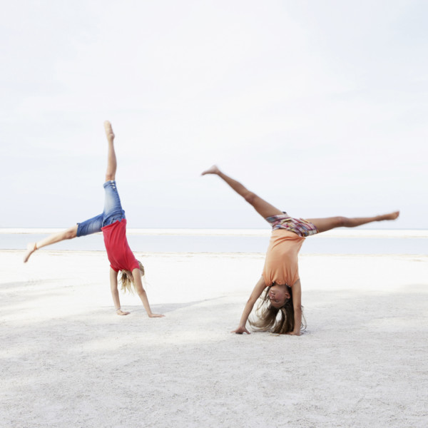 Girls doing cartwheels on beach. Date : 2008