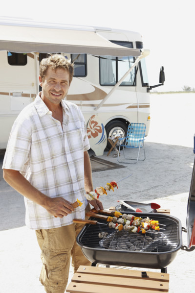 Man grilling shish kebabs on beach. Date : 2008