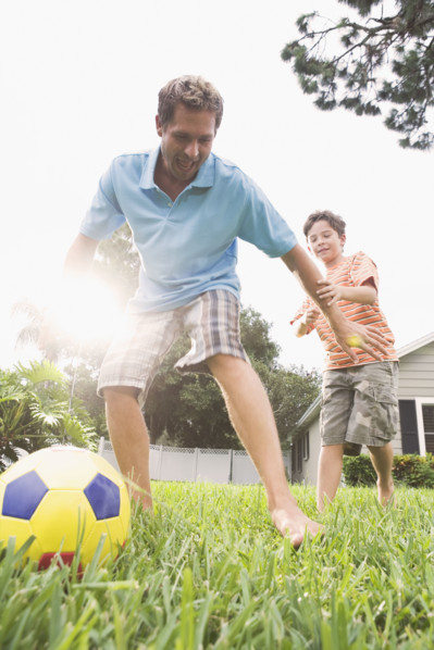 Father and son playing soccer in backyard. Date : 2008