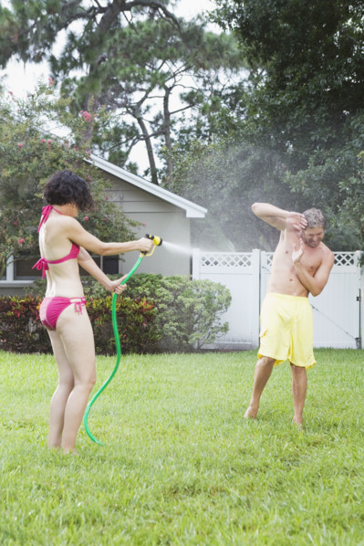 Woman spraying man with hose in backyard. Date : 2008