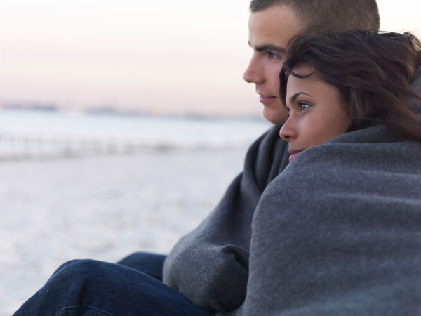 Young couple wrapped in blankets on beach. Date : 2008