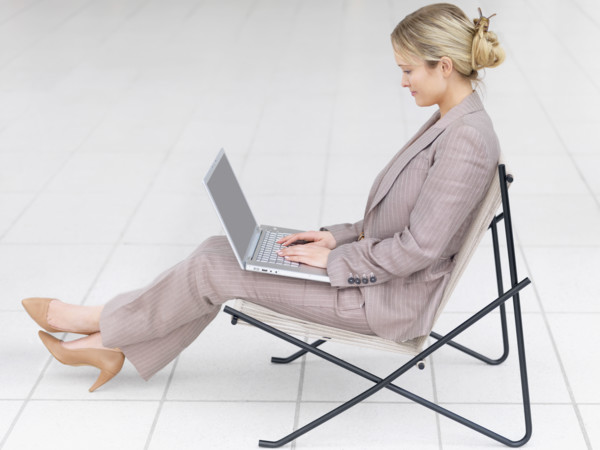 Businesswoman working on laptop in modern chair. Date : 2008