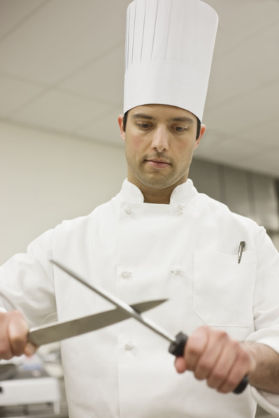 Chef sharpening knife in kitchen. Date : 2008