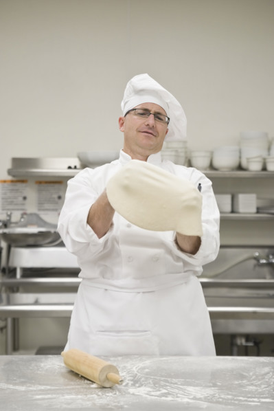 Chef stretching pizza dough. Date : 2008
