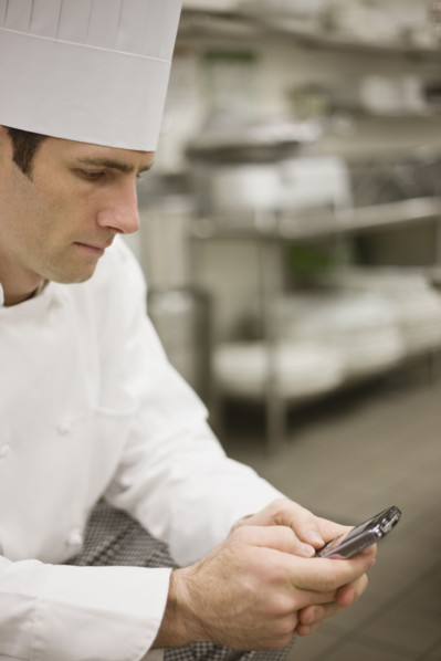Chef in uniform checking text messages. Date : 2008