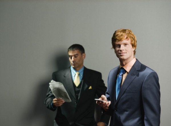 Businessmen holding newspaper and cell phone. Date : 2008