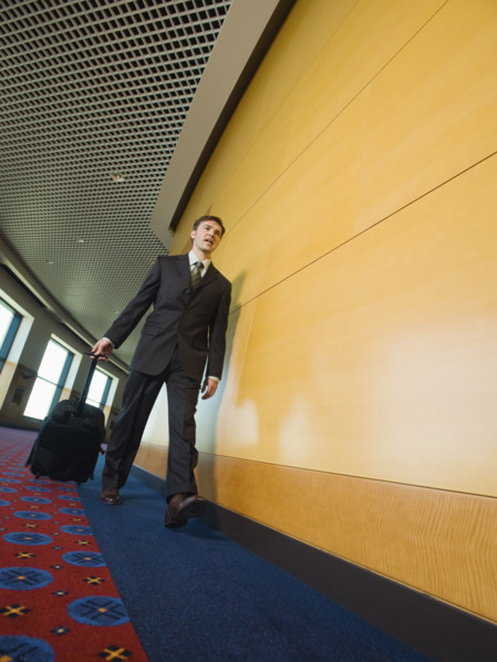 Businessman pulling suitcase in office corridor. Date : 2008